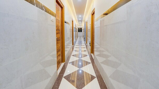 Un pasillo de hotel con paredes de mármol, piso de diseño geométrico y puertas de madera.