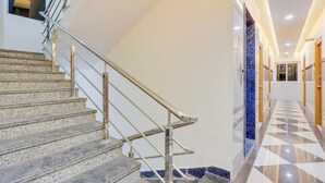Interior moderno de hotel con una escalera, piso a cuadros y un pasillo que conduce a una habitación.