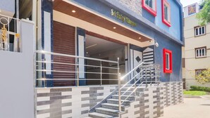 Un edificio con una escalera que conduce a un acceso cubierto, un letrero que dice 'Sri Rajah Muralay' y un diseño moderno con una mezcla de materiales.