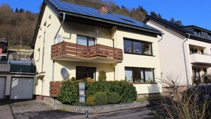 Una casa moderna de dues plantes amb un balcó, panells solars i un garatge.