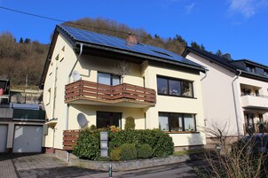 Una casa moderna de dos pisos con balcón, paneles solares y garaje.