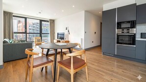 Un apartamento moderno con comedor, sofá, cocina equipada y ventanas amplias con vista a la ciudad.
