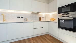 Una cocina moderna con armarios blancos, un horno Bosch y piso de madera.
