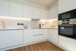 A modern kitchen with white cabinets, a Bosch oven, and a wooden floor. - Modern City Elegance (London)