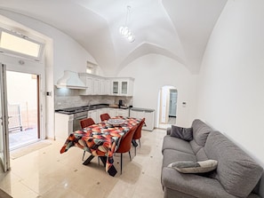 A compact living space with a dining area, kitchenette, and a sofa. - Dimora De Pace - Salento Reservation (Gallipoli)