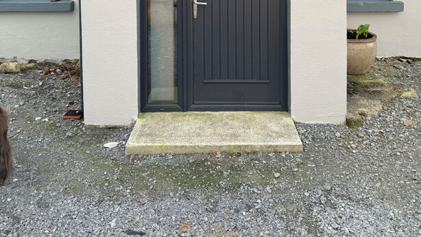 A building with a dark-colored door, a small window, and a nameplate. - A little slice of heaven! (Rosmuc)