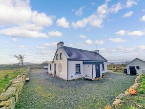 A white house with a blue roof, a stone wall, and a gravel driveway. - A little slice of heaven! (Rosmuc)