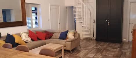 Una sala de estar con sofá, mesa de centro y una escalera.