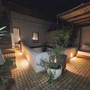 A courtyard with a white bench, potted plants, and a tiled floor. - Petit Pacha Your Ultimate Escape Awaits you (Marrakech)