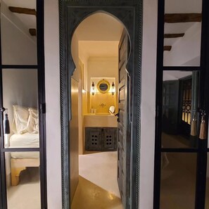 A hallway leading to a bathroom with a mirror, lights, and a small cabinet. - Petit Pacha Your Ultimate Escape Awaits you (Marrakech)
