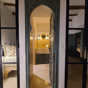 A hallway leading to a bedroom with a bed, a mirror, and a small vanity area. - Petit Pacha Your Ultimate Escape Awaits you (Marrakech)