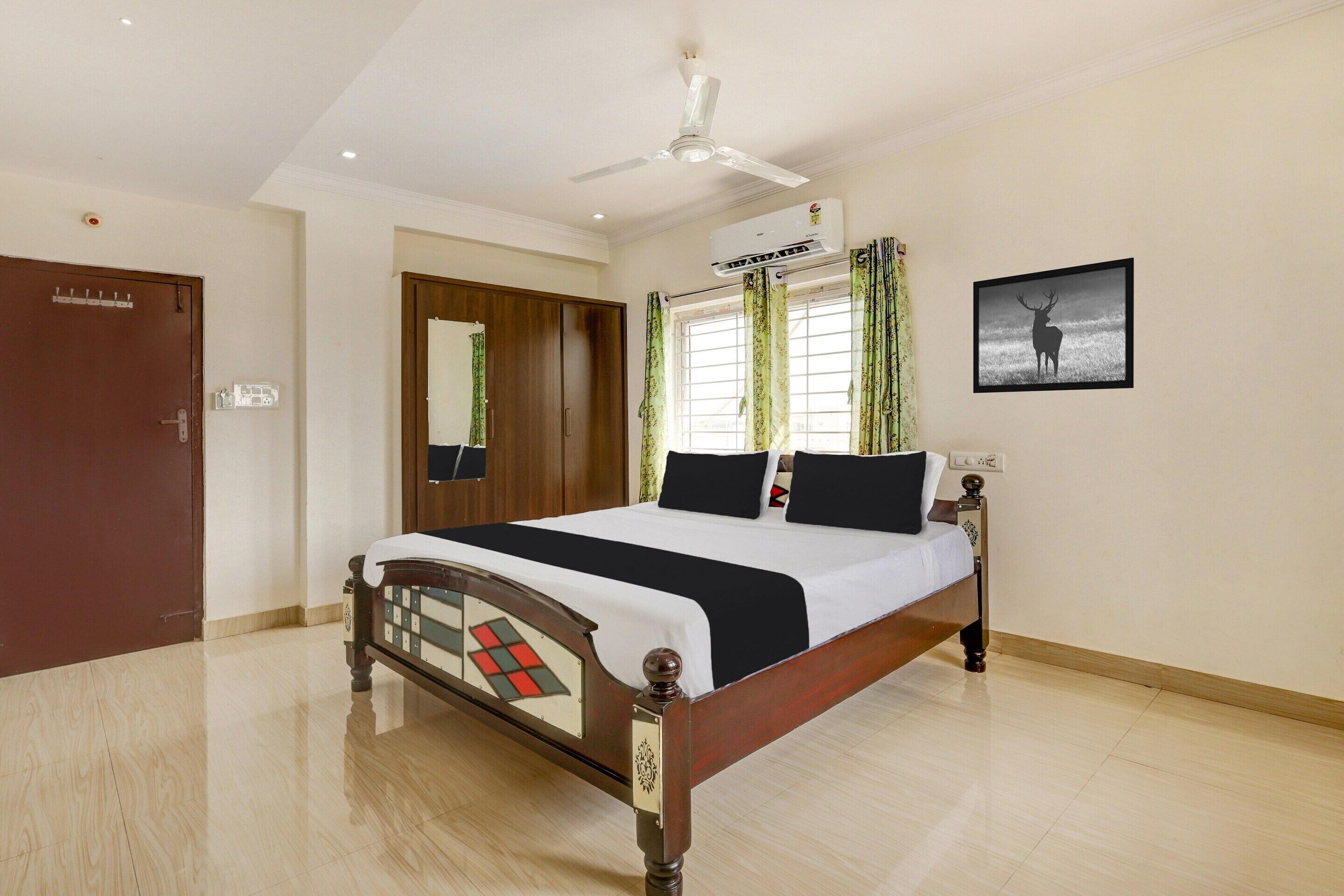 Une chambre à coucher comprenant un lit, un ventilateur de plafond, un appareil de climatisation, une fenêtre avec des rideaux et un tableau accroché au mur.