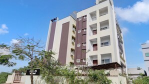 A multi-story residential building with balconies, a sign indicating 'HUELO,' and a clear blue sky. - Classic With Balcony The Best Inn (Kakinada)