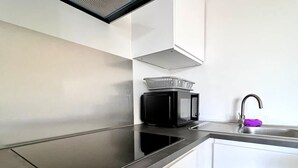 Une cuisine moderne dotée d’une plaque de cuisson à induction noire, d’un four à micro-ondes et d’un évier en acier inoxydable.