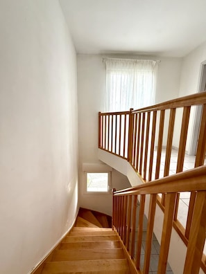 Un escalier en bois, doté d’une rampe, menant à un palier.
