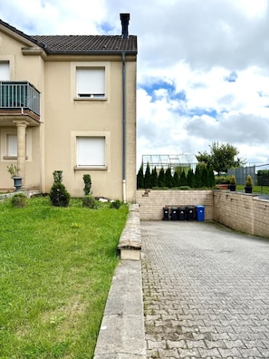 Un immeuble résidentiel doté d’une allée pavée, d’un petit jardin et d’une serre.