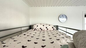 A bedroom with a bed, a wall clock, and a window. - Small Cozy Nest for 4 People 100 m From the Beach Free Parking (De Haan)