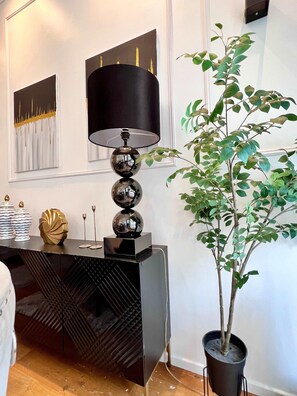 Una habitación moderna con una consola negra, una planta en maceta y obras de arte en la pared.