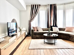 A modern living room with a sofa, coffee table, and TV. - Sablon Centre Cozy Apartment Near the Museums (Brussels)