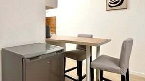 Eine kleine Küche mit einem Kühlschrank, einem Esstisch und zwei Stühlen.