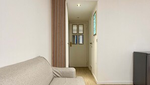 Ein Wohnzimmer mit einer Couch, einer Wand aus Holzslattern, einer Tür mit Fenstern und einem kleinen Schrank.