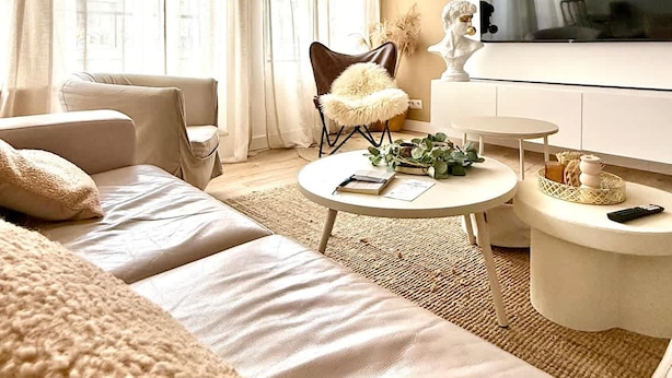 A modern living room with a sofa, a coffee table, a TV, and a decorative sculpture. - Spacious Duplex in the Center of Bastogne Onikos Rooms (Bastogne)