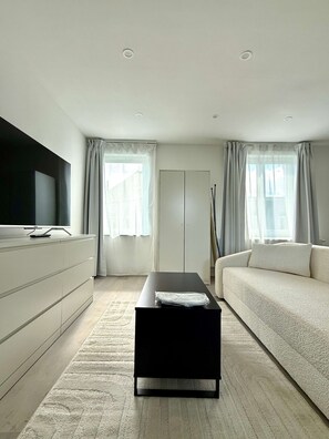 En moderne stue med et fladskærms-tv, en sofa, et sofabord og et klædeskab.