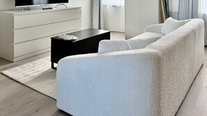 A modern living room with a flat-screen TV, a sofa, a coffee table, and a wardrobe. - Doux nid Perche Avec vue Magique sur la Ville (Brussels)