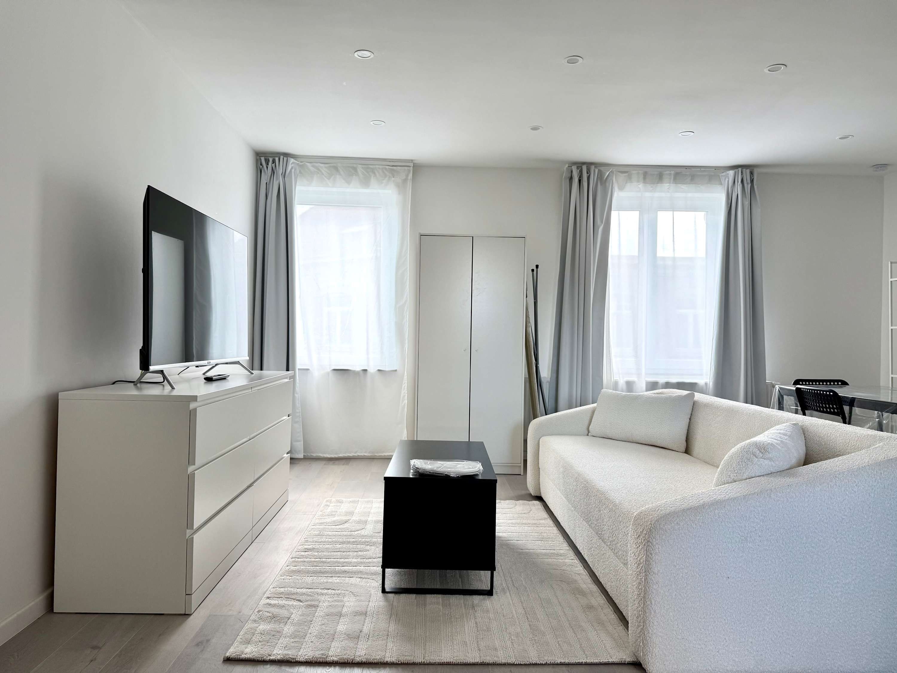 Een moderne slaapkamer met een bed, bureau, dressoir en televisie.
