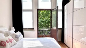 Une chambre à coucher comprenant un lit, une armoire et un balcon avec vue sur la verdure.