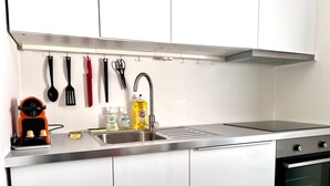 Une cuisine moderne dotée d’un évier en acier inoxydable, d’un four encastré et de divers ustensiles de cuisine suspendus au-dessus de l’évier.