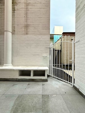 A courtyard with a white bench, a metal gate, and a brick wall. - Studio Moderne au Coeur du Quartier Saint Adalbert (Liege)