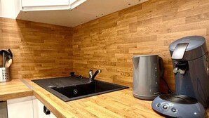 Une cuisine avec un plan de travail en bois, un évier, une machine à café et un placard.