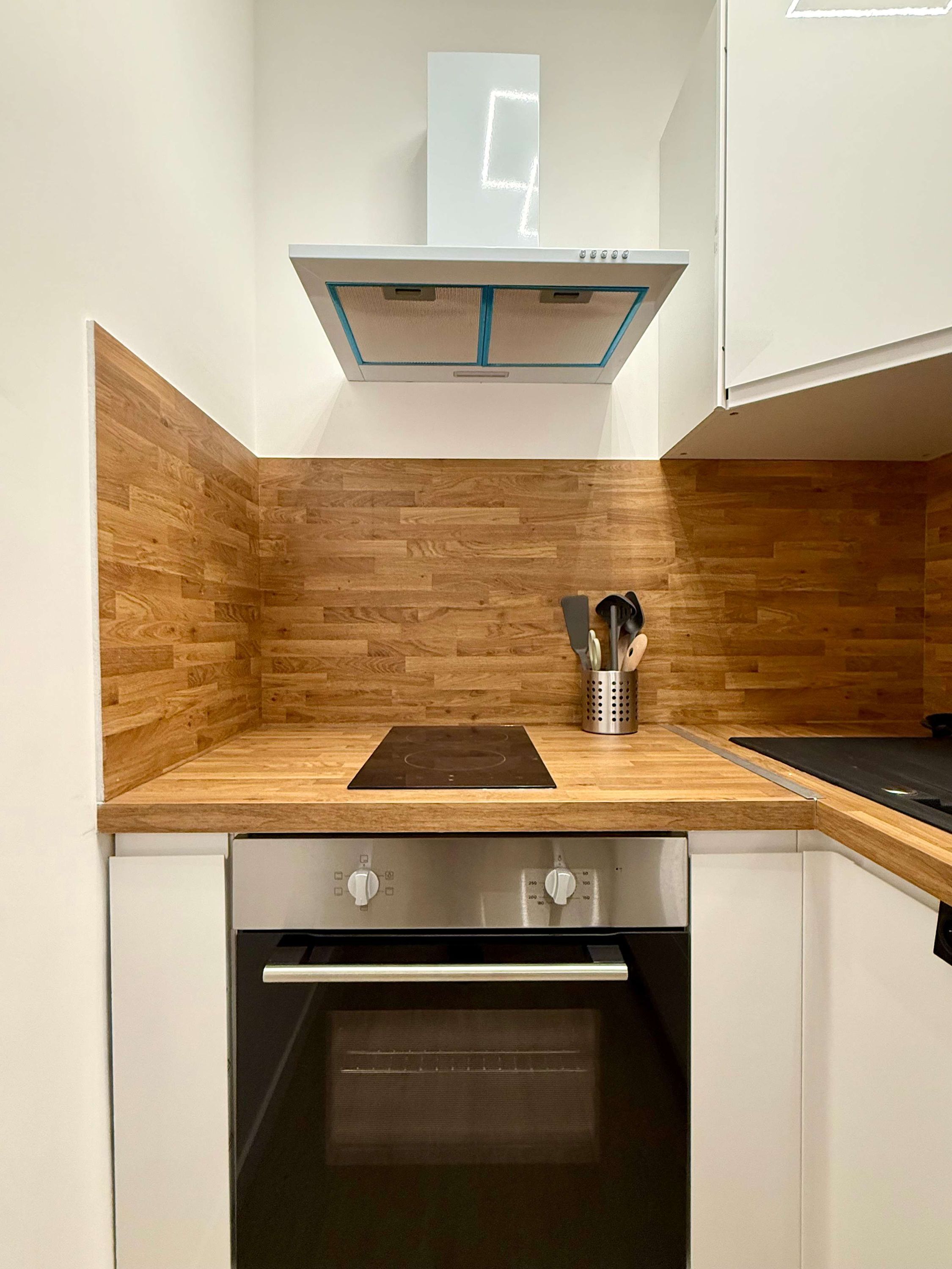 A kitchen with wooden cabinetry, a built-in oven, and a stainless steel range hood.