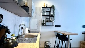 Ett modernt kök med en bänkskiva i trä, en diskho, en spis och en matplats med ett bord och stolar.