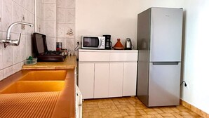 Eine Küche mit Spüle, Mikrowelle, Wasserkocher und Kühlschrank.