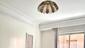 Ein Wohnzimmer mit einem beigen Sofa, einem gemusterten Teppich, einem Holztisch und einer dekorativen Deckenleuchte.