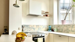 Une cuisine moderne dotée d’un îlot central, de meubles blancs, d’une cuisinière et d’une fenêtre agrémentée d’une plante.