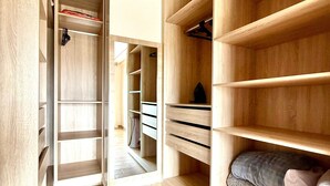 A walk-in closet with wooden shelving and drawers, a bed with pillows, and a tiled floor. - Villa With Pool Rooftop Near Amelkis and Al Maaden Golf Courses Route de Ouarzazate Area (Marrakech)