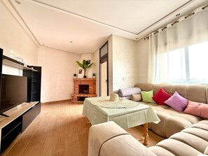 Ein Wohnzimmer mit Kamin, einer Couch, einem Fernseher und einem Tisch mit Unterlage.