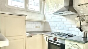 A kitchen with white cabinetry, a gas stove, an oven, and a window with a view of buildings. - 3 min to the Grand-place 6 min to Manneken Pis Sleeps 6 (Brussels)