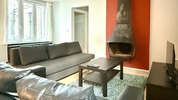 A modern living room with a sofa, coffee table, fireplace, and a television. - 3 min to the Grand-place 6 min to Manneken Pis Sleeps 6 (Brussels)