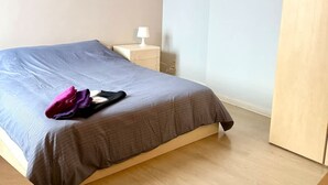 A bedroom with a bed, a nightstand, a lamp, and a wooden wardrobe. - 3 min to the Grand-place 6 min to Manneken Pis Sleeps 6 (Brussels)