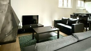 A modern living room with a sofa, a coffee table, a TV, and a dining area with chairs and a table. - 3 min to the Grand-place 6 min to Manneken Pis Sleeps 6 (Brussels)