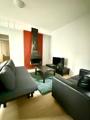 A modern living room with a fireplace, a sofa, a coffee table, and a television. - 3 min to the Grand-place 6 min to Manneken Pis Sleeps 6 (Brussels)