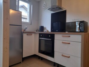 Cocina compacta con refrigerador, horno, microondas y ventana que proporciona luz natural.