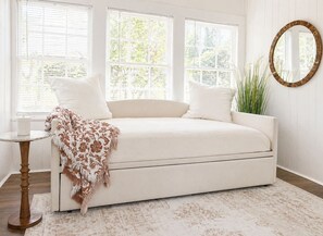 A room with a sofa, a round mirror, and a plant.