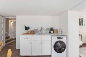 Eine kleine Küche mit integriertem Waschbecken, Spüle und einer Arbeitsplatte mit diversen Gegenständen.