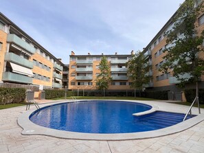 A residential building with a swimming pool, balconies, and a central tree. - Garden & Pool apartment 8 persons (Tossa de Mar)
