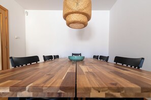 A conference room with a wooden table, black chairs, a woven light fixture, and a teal bowl on the table. - Garden & Pool apartment 8 persons (Tossa de Mar)
